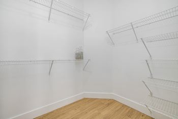 a room with white walls and shelves and a wood floor